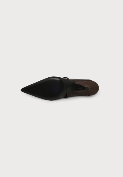 Chaussure à talon haut marron à bout pointu vue de dessous, avec une semelle noire et un talon fin sur fond blanc.
