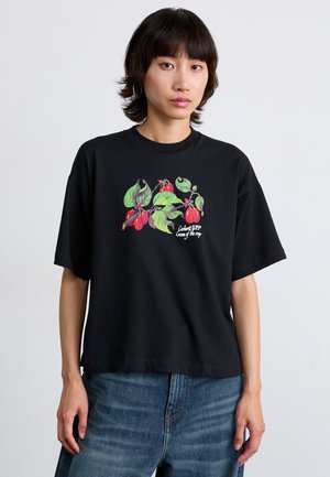 T-shirt en coton noir à manches courtes avec un imprimé floral coloré en vert et rouge. Coupe décontractée avec un col rond.
