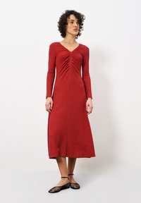 Rotes Langarmkleid mit V-Ausschnitt und gerafften Details an der Vorderseite. Hergestellt aus strukturiertem Stoff, hat es einen knie-langen Rock und eine figurbetonte Silhouette.