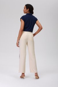 Marineblauw short-sleeve shirt gecombineerd met crèmekleurige wijde broek. De broek heeft zijaccenten en een gladde textuur; het shirt heeft een kraag en een achternaad.