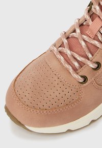 Rózsaszín sportos sneaker, velúr és hálós felsőrésszel, perforált textúrával, kerek orral és kontrasztos fehér talppal. Díszes fűzőkkel és fűzőlyukakkal rendelkezik.