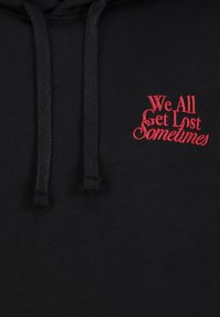 Black hoodie featuring red embroidered text "We All Get Lost Sometimes," with drawstrings and a soft fabric texture.