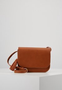 Bruine faux leren crossbodytas met een klepsluiting, verstelbare riem en decoratieve tassel. Soepele textuur met effen kleur.