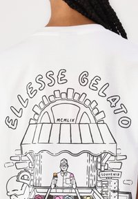 Camiseta blanca con un dibujo en línea negro de un puesto de gelato que lleva el texto "ELLESSE GELATO", representando a un vendedor sosteniendo dos conos de helado.