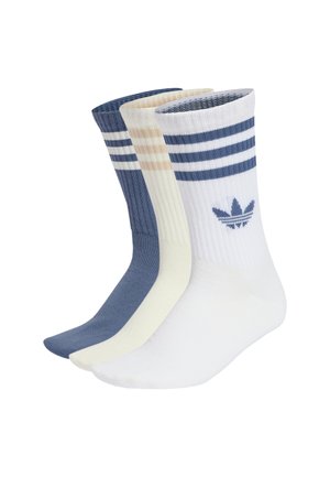 Tre paia di calzini a costine a gamba corta in bianco, crema e blu, ciascuno con due strisce orizzontali vicino alla parte superiore e un logo trifoglio sul bordino.