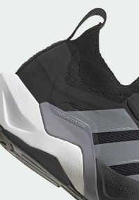 Sort atletiksko med mesh-stof, gummisål og et karakteristisk torsionssystem. Grå detaljer forbedrer designet.