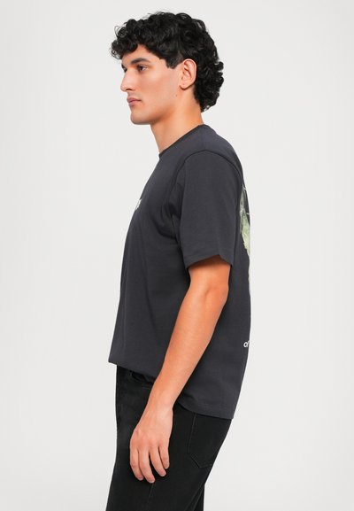 Camiseta de algodón negra con mangas cortas, corte holgado, escote redondo, con un diseño gráfico en la parte posterior.