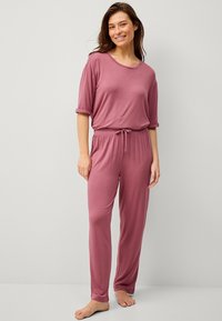 Zacht, lichtgewicht, roze lounge-set met een elastische taille en trekkoord. Gladde textuur en een ontspannen pasvorm. Geen zichtbare patronen of hardware.