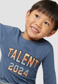 Blaues Langarm-T-Shirt mit bold grafischem Text "TALENT 2024" in Farbverlauf. Weicher Stoff mit Rundhalsausschnitt und normaler Passform.