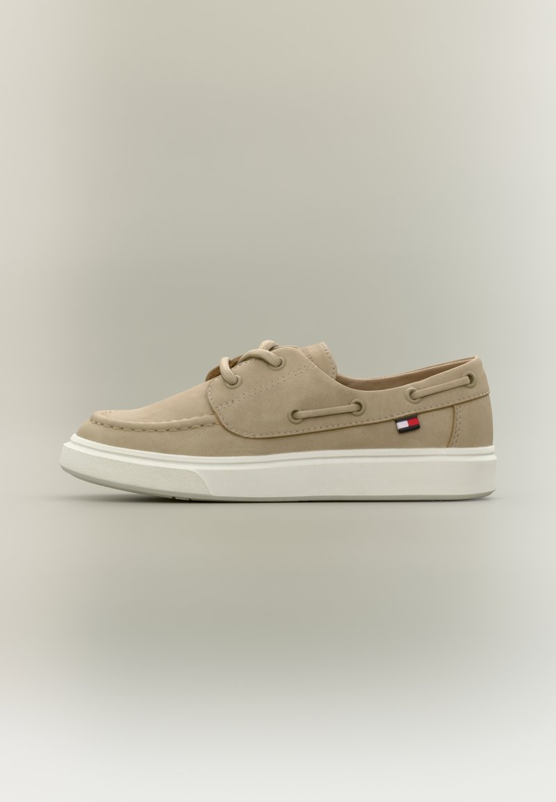 Μπεζ καστόρινες μοκασίνια με λευκές λαστιχένιες σόλες, σχέδιο με κορδόνια και μικρό λογότυπο σε κόκκινο, λευκό και μπλε στο πλάι.