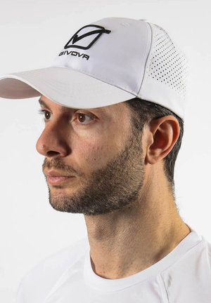 Uomo con barba corta che indossa un cappellino da baseball bianco forato con il logo nero Givova e una camicia bianca, volto verso sinistra.