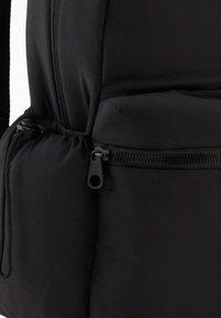 Sac à dos noir avec une coque extérieure douce et rembourrée. Comprend une poche zippée et des bretelles ajustables. Matériau texturé avec une finition lisse.