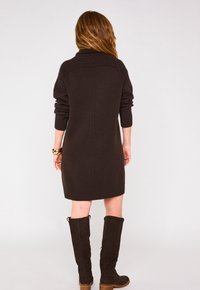 Abito lavorato a maglia marrone scuro con collettino a girocollo a coste e maniche lunghe, rifinito con orlo a coste. Stivali in suede al ginocchio completano l'outfit.
