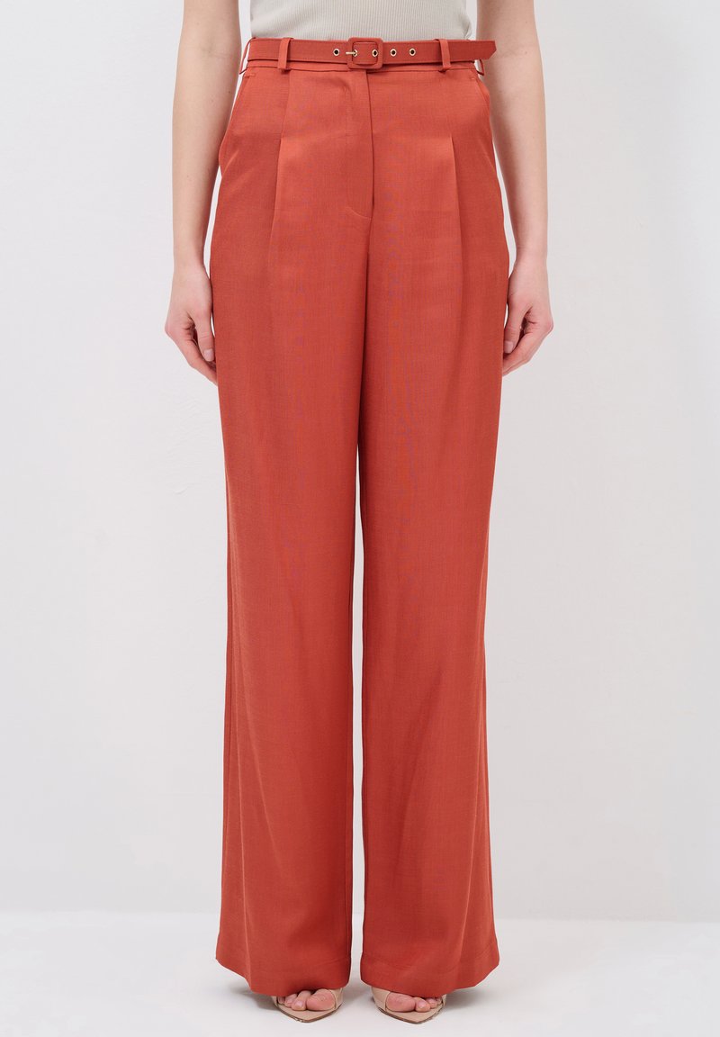 Wide-leg trousers in rust orange fabric with a smooth texture, featuring a fitted waistband and a matching belt with metal accents.
