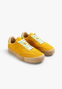 Sneakers gialli in suede con suole in gomma tan testurizzate e lacci azzurri. Presentano cuciture curve e una fodera interna liscia.