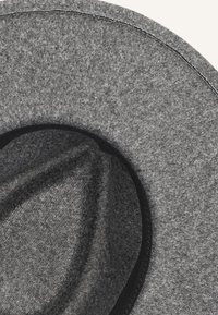 Grijze vilten hoed met een brede, gestructureerde rand, met een gladde textuur en een zwarte binnenband. De rand is omlijnd met stikwerk.