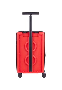 Hard-shell suitcase with a red exterior, black accents, and a retractable handle. Features two circular indentations on the back and four wheels.