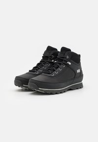 Botas de senderismo negras de caña media, con un upper sintético liso, cordones reforzados, suela de goma con patrones de tracción y acento de logo.