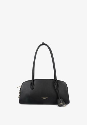 Black leather handbag with zip closure, dual rounded handles, and gold hardware. Features a logo detail and a small detachable tag.