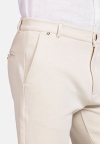 Beige tapered broek van een katoenmix, met een gladde textuur, zijzakken en een klein Italiaans vlagaccent bij de tailleband.