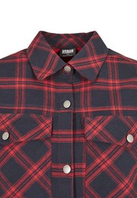 Rutigt flanellskjorta i marinblått och rött, med klassisk krage, silverfärgade tryckknappar och två framfickor. Texturerad tyg med rutmönster.