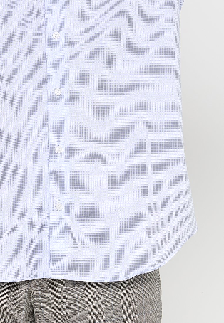 Camisa de manga corta de color azul claro con un sutil patrón de cuadros, presenta un cierre de botón y un dobladillo curvado. Está hecha de una tela ligera.