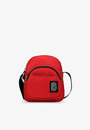 Bolso bandolera de nylon rojo con correa ajustable, forma redondeada, bolsillo con cremallera en la parte frontal y parche de logo negro. Textura suave y diseño minimalista.
