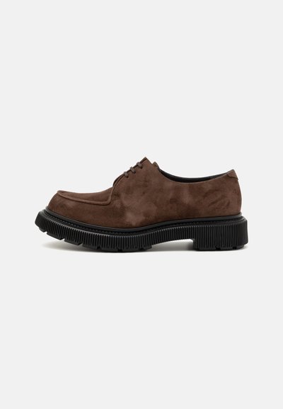 Brown suede oxford shoes with a thick black rubber sole, featuring textured detailing and a classic lace-up design.