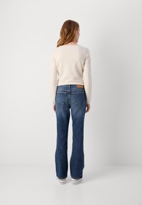 Sinised laiad teksad keskmise pesu ja denimsinise materjali puhul, millel on taga vöökohtades väike helepruun nahast silt. Kombineeritud kreemika kampsuniga.