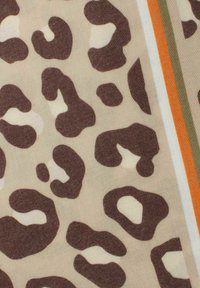 Leopardenmusterstoff mit unregelmäßigen braunen Flecken auf einem beigen Hintergrund, mit Streifen in Orange und Grün. Weiche Textur und leichtes Design.