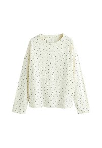 Langærmet cremefarvet skjorte lavet af blødt stof med et spredt sort polkaprikket mønster, med rund halsudskæring og raglanærmer.