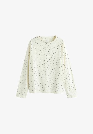 Chemise crème à manches longues en tissu doux, présentant un motif dispersé de pois noirs, avec un col rond et des manches raglan.