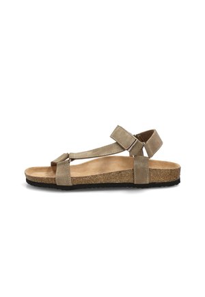 Sandalia beige de punta abierta con tiras ajustables, plantilla de corcho y suela negra texturizada mostrada de perfil.