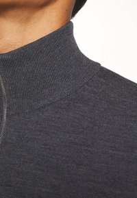 Grau hochgeschlossenes Sweatshirt mit gerippter Textur und subtiler Glanz. Verfügt über einen Reißverschluss am Hals und ein figurnahes Design.