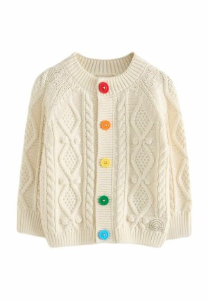 Cremefarbener gestrickter Cardigan mit Zopfmustern, ausgestattet mit sechs bunten Knöpfen. Beinhaltet ein kleines Logo-Patch unten rechts.