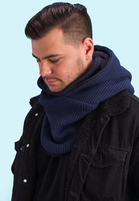 Dark blue knitted scarf wrapped around the neck, with a textured pattern. The wearer is in a black jacket with a fuzzy collar.