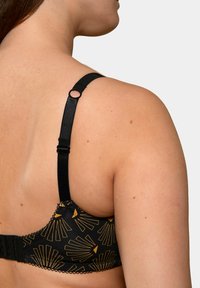 Soutien-gorge noir avec motif géométrique doré, doté d'une bride réglable et d'une fermeture à crochets, avec un bord festonné sur la bande.