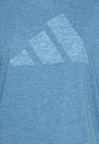 Camiseta deportiva azul con textura jaspeada, que presenta un sutil logo de tres franjas en un tono más claro en el frente.