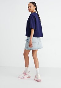 Marineblå cropped t-shirt, denimskørt med lommer, lys denimvask, parret med lyserøde og hvide sneakers og hvide flæse-sokker.