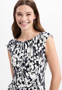 Marine jurkje met wit bloemenpatroon, kapmouwen en gedrapeerde textuur. Bevat een ronde halslijn en een aansluitende silhouet.