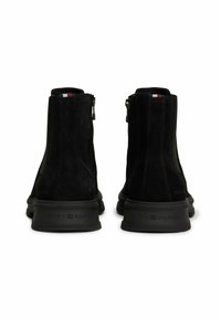 Zwarte suède enkelboots met zijknippers, rubberen zolen en een logo op de hak. Heeft een driekleurig accent in rood, wit en blauw.