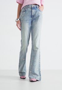 Lichtblauwe uitlopende jeans met bloemenborduurwerk op de voorkant, gemaakt van denim. Heeft een hoge taille en een iets vervaagde afwerking.