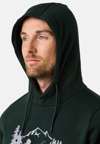 Felpa con cappuccio di un verde scuro, caratterizzata da un cappuccio con cordino, una texture morbida e un design frontale con grafiche bianche di montagne e foreste.