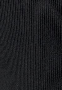 Tecido ribado preto com um padrão texturizado, apresentando linhas verticais. O material parece suave e flexível.