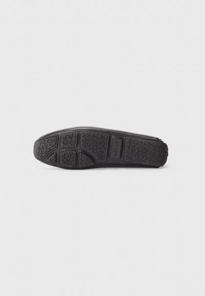 Talpa neagră de pantof plat, cu cauciuc texturat și un model de aderență. Include detalii de branding pe laturi, fiind concepută pentru confort și durabilitate.