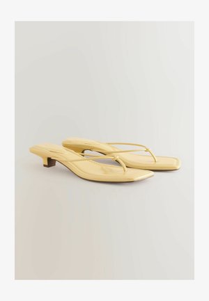 Geltoni dirbtinės odos šlepetės su žemu blokiniu kulnu, turinčios minimalistinį tarpdančio dizainą ir kvadratinę noselę. Lygus paviršius, elegantiškas apdaila.