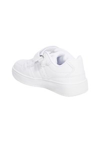 Zapatilla blanca con un upper sintético liso, tira de velcro, cuello acolchado y suela de goma texturizada. Presenta detalles perforados en el costado.