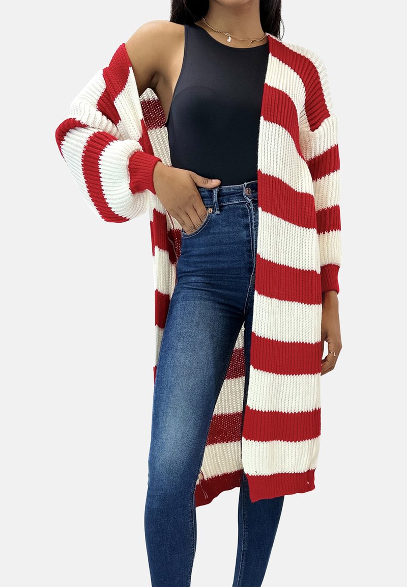 Czerwono-biały pasiasty sweter na drutach z otwartym przodem, szerokimi rękawami i prążkowaną fakturą, noszony na czarnym topie i niebieskich jeansach.