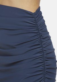 Gonna blu navy con arricciatura realizzata in tessuto morbido, caratterizzata da una texture arricciata lungo il lato e una vita liscia per una vestibilità aderente.