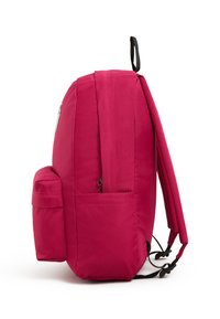 Vaippulaukku vaaleanpunaisesta kankaasta, joka on pyöreän muotoinen, säädettävillä olkaimilla, sivutaskulla ja vetoketjukiinnityksillä. Tasainen pinta ilman näkyviä kuvioita.